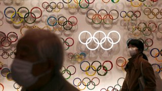 Two people wear masks as they visit the newly opened Japan Olympic Museum located near the New National Stadium, Sunday, Feb. 23, 2020, in Tokyo. (AP Photo/Jae C. Hong)