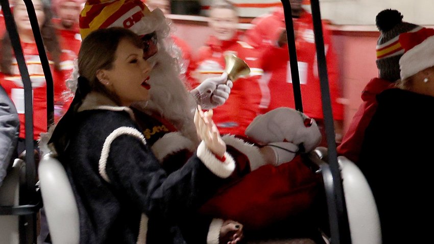 Taylor Swift waves to fans on a golf cart with Santa Claus