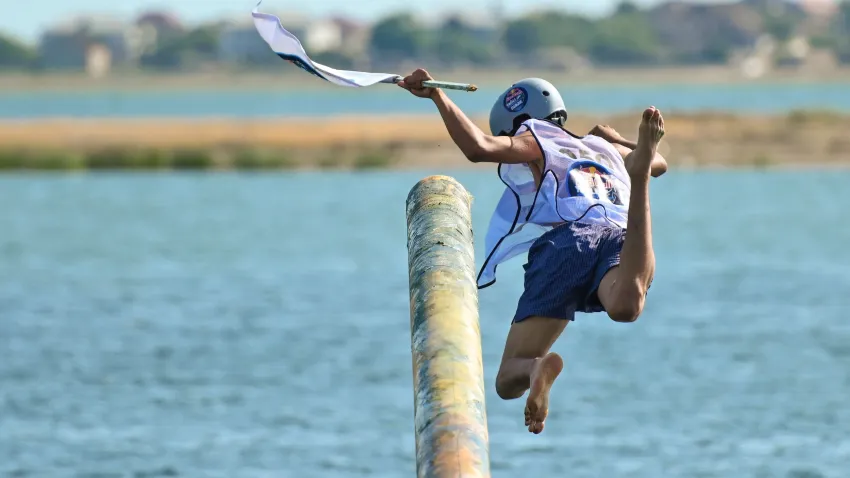 Person falls off greased telephone pole over water