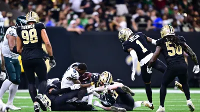 NEW ORLEANS, LOUISIANA – SEPTEMBER 22: DeVonta Smith #6 of the Philadelphia Eagles loses his helmet after being tackled by Paulson Adebo #29 and Kendal Vickers #91 of the New Orleans Saints at Caesars Superdome on September 22, 2024 in New Orleans, Louisiana. (Photo by Gus Stark/Getty Images)