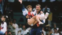 Kerri Strug of the United States is carried by coach Bela Karolyi